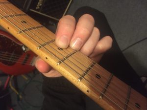Muting the 2nd String with the edge of the 1st finger.